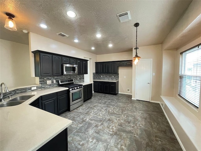 kitchen with backsplash, a textured ceiling, stainless steel appliances, sink, and pendant lighting