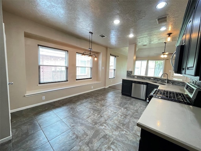 kitchen featuring ceiling fan, pendant lighting, a textured ceiling, and appliances with stainless steel finishes