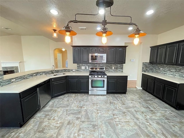 kitchen with sink, stainless steel appliances, backsplash, pendant lighting, and a textured ceiling