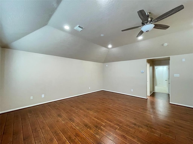 empty room with a textured ceiling, dark hardwood / wood-style flooring, vaulted ceiling, and ceiling fan