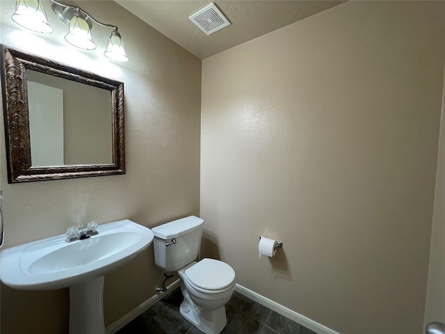 bathroom with tile patterned flooring, a textured ceiling, toilet, and sink