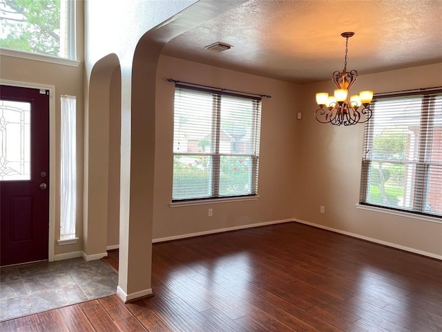 entrance foyer featuring dark hardwood / wood-style floors, a textured ceiling, and an inviting chandelier