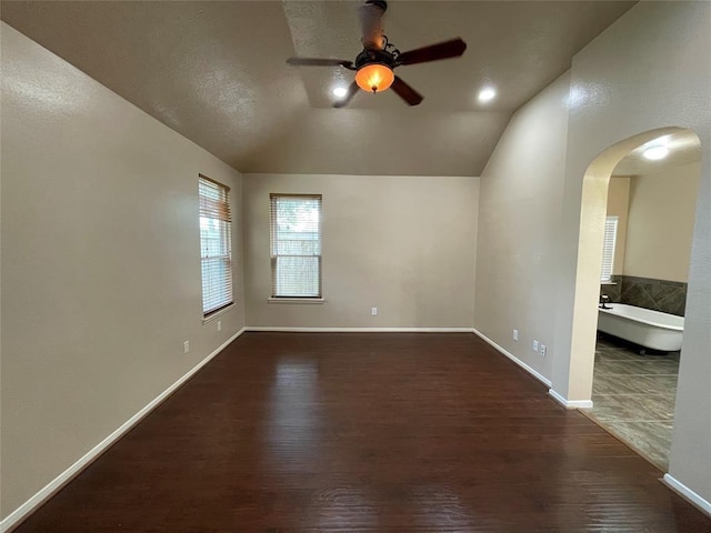 empty room with ceiling fan, dark hardwood / wood-style floors, and lofted ceiling