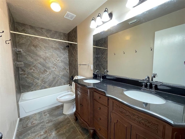 full bathroom featuring a textured ceiling, vanity, toilet, and tiled shower / bath