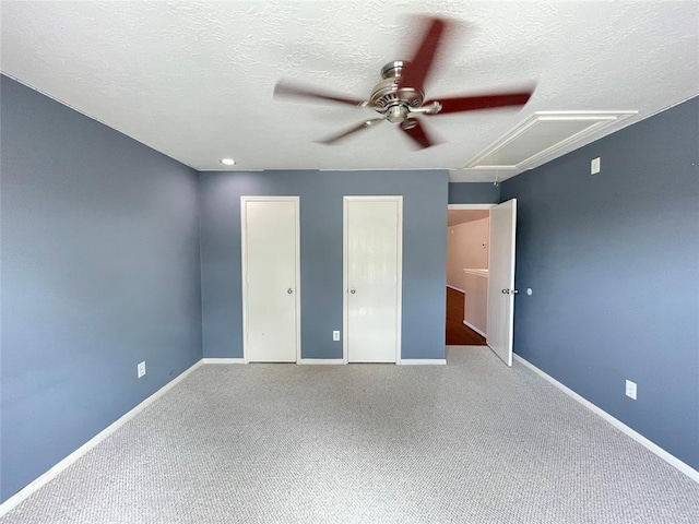 unfurnished bedroom with ceiling fan, carpet floors, a textured ceiling, and two closets