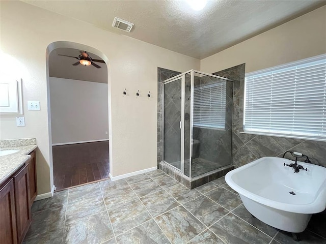 bathroom featuring vanity, a textured ceiling, ceiling fan, and plus walk in shower