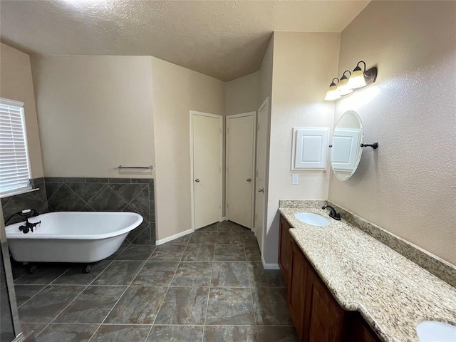 bathroom featuring a textured ceiling, vanity, and a bathing tub