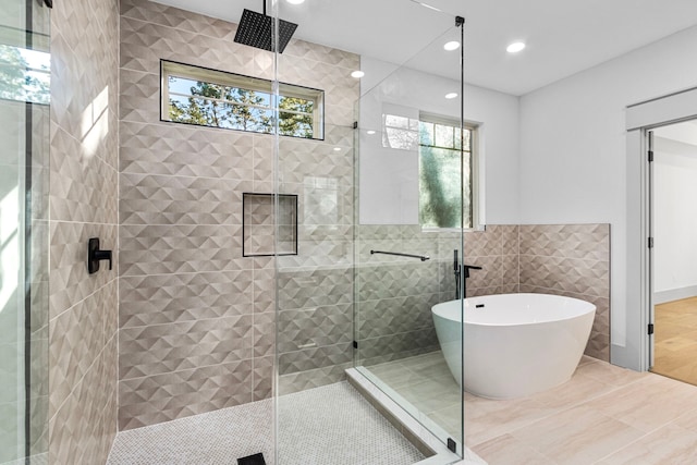 bathroom with shower with separate bathtub, tile patterned floors, and tile walls