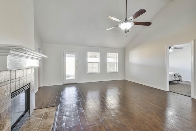 unfurnished living room with dark hardwood / wood-style floors, high vaulted ceiling, and a tile fireplace