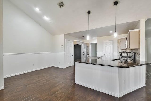 kitchen with sink, stainless steel fridge, dark wood-type flooring, decorative light fixtures, and kitchen peninsula