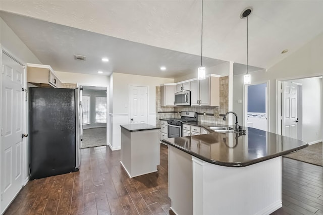 kitchen featuring sink, stainless steel appliances, a kitchen island, decorative light fixtures, and a barn door