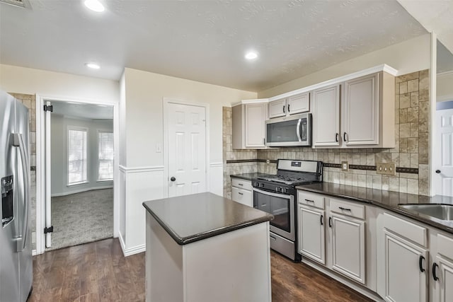 kitchen with tasteful backsplash, stainless steel appliances, dark hardwood / wood-style flooring, and a kitchen island