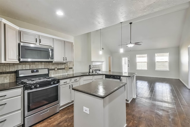 kitchen with vaulted ceiling, appliances with stainless steel finishes, sink, hanging light fixtures, and kitchen peninsula