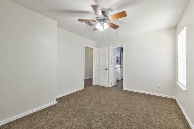 spare room featuring dark carpet and ceiling fan