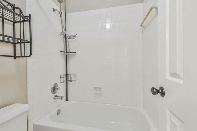 bathroom featuring tiled shower / bath combo and toilet