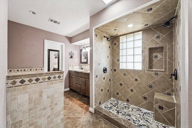 bathroom with tile walls, tiled shower, and vanity