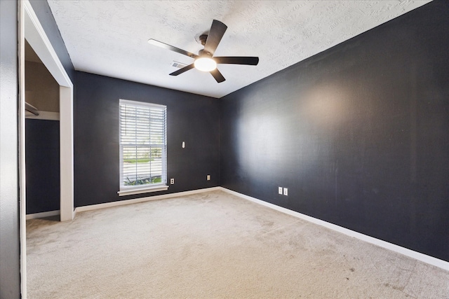 carpeted empty room with ceiling fan and a textured ceiling