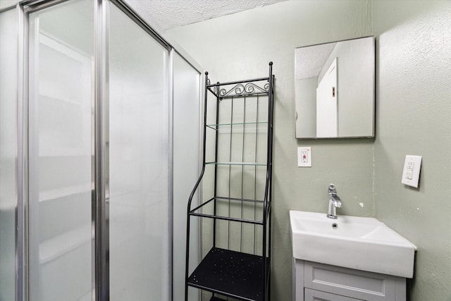 bathroom featuring a textured ceiling, walk in shower, and vanity