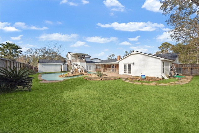 back of house with a fenced in pool, a yard, a storage shed, and a patio