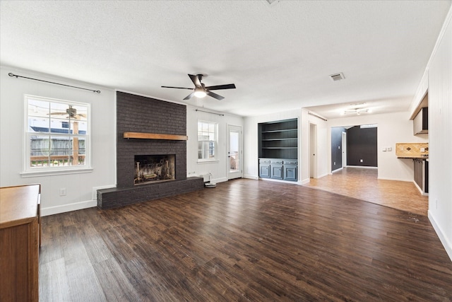 unfurnished living room featuring a wealth of natural light, dark wood-type flooring, and a fireplace