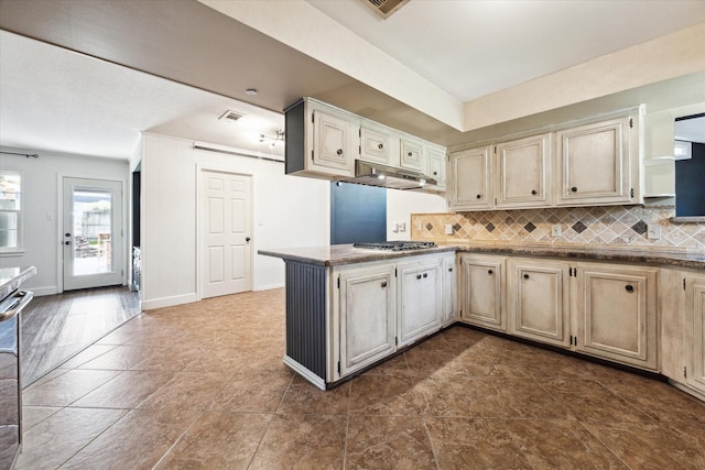 kitchen featuring backsplash, kitchen peninsula, and stainless steel gas cooktop