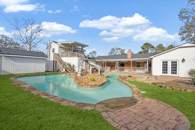 view of swimming pool featuring a lawn, a water slide, french doors, and a patio