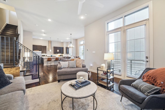 living room with dark wood-type flooring and ceiling fan with notable chandelier