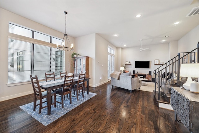 dining space with dark hardwood / wood-style flooring and ceiling fan with notable chandelier