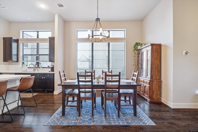 dining area with a healthy amount of sunlight, dark hardwood / wood-style flooring, sink, and a chandelier