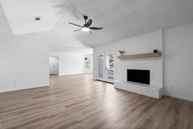 unfurnished living room with vaulted ceiling, hardwood / wood-style flooring, ceiling fan, a fireplace, and a textured ceiling