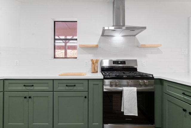 kitchen with wall chimney exhaust hood, stainless steel gas stove, tasteful backsplash, and green cabinetry