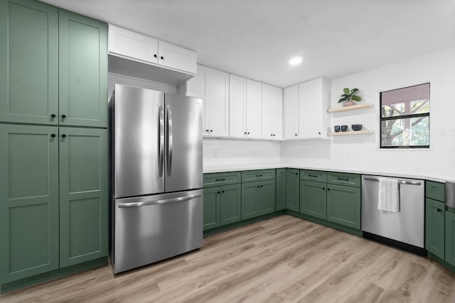 kitchen with decorative backsplash, stainless steel appliances, green cabinetry, white cabinets, and light hardwood / wood-style floors