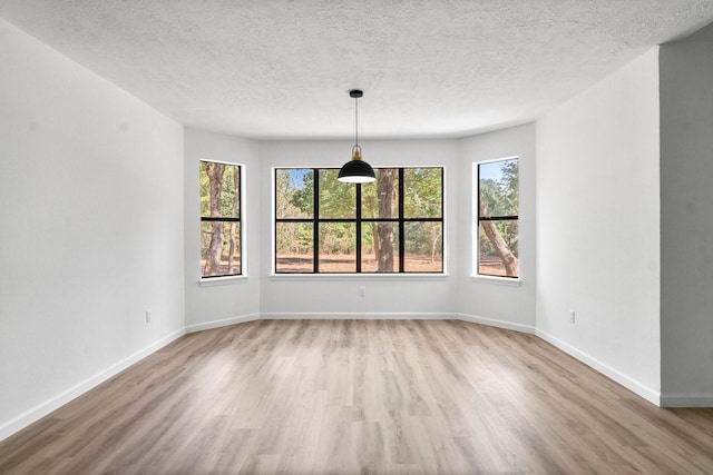 unfurnished room with light wood-type flooring and a textured ceiling