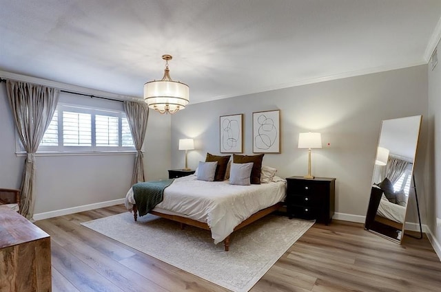 bedroom featuring an inviting chandelier, light hardwood / wood-style flooring, and crown molding