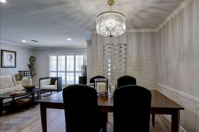 dining space with wood-type flooring, a chandelier, and ornamental molding