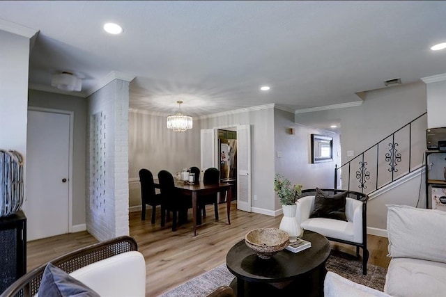 living room featuring a notable chandelier, light wood-type flooring, and ornamental molding