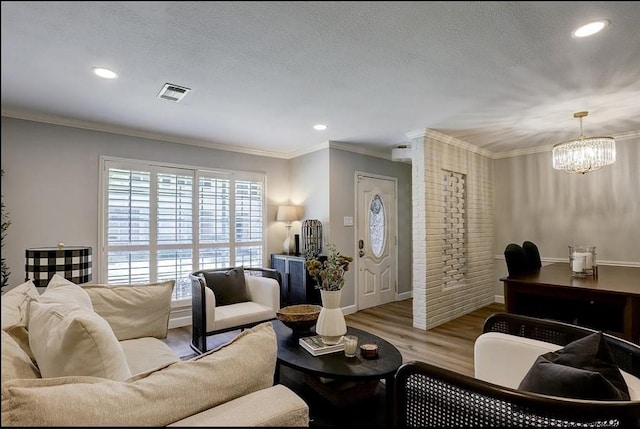 living room featuring a textured ceiling, light hardwood / wood-style floors, crown molding, and a chandelier