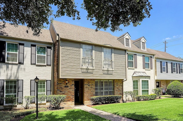 multi unit property featuring brick siding and a front lawn