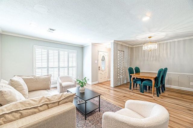 living room with light wood finished floors, a notable chandelier, a textured ceiling, and crown molding