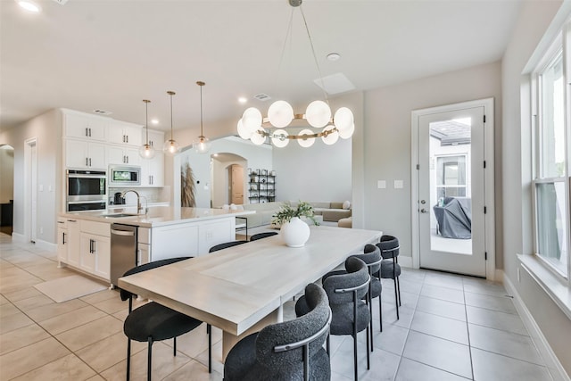 dining space featuring light tile patterned flooring, sink, and an inviting chandelier