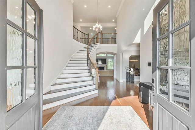 foyer featuring a towering ceiling, dark wood-type flooring, and a notable chandelier