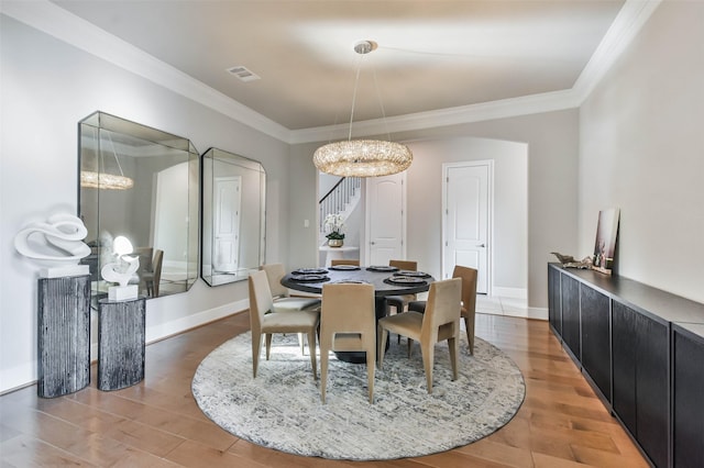 dining space featuring hardwood / wood-style floors, a notable chandelier, and crown molding