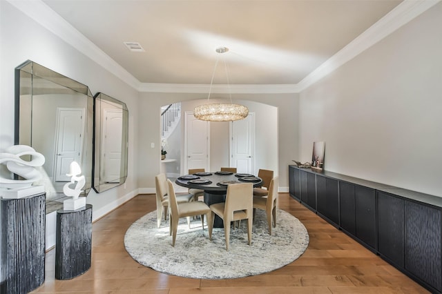 dining space with crown molding, a chandelier, and wood-type flooring