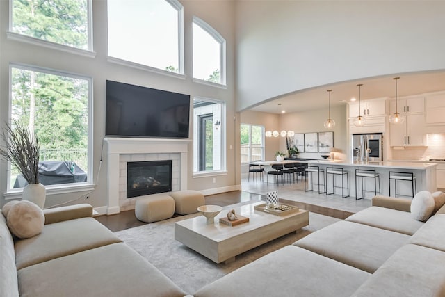 living room with sink, light wood-type flooring, a high ceiling, and a tile fireplace