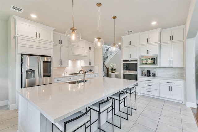 kitchen featuring white cabinets, a kitchen island with sink, hanging light fixtures, and appliances with stainless steel finishes