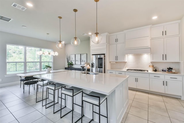 kitchen with white cabinets, a spacious island, sink, decorative light fixtures, and stainless steel appliances