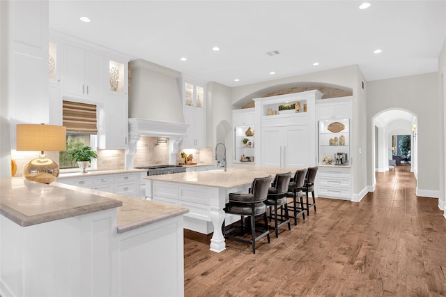 kitchen featuring backsplash, a large island, white cabinets, and custom range hood