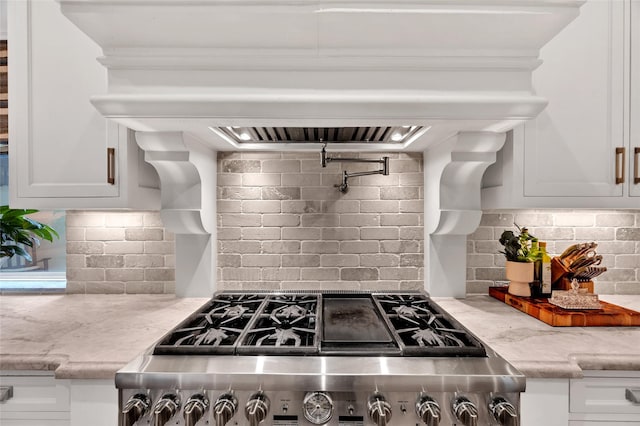 kitchen with white cabinets, range, light stone counters, and decorative backsplash