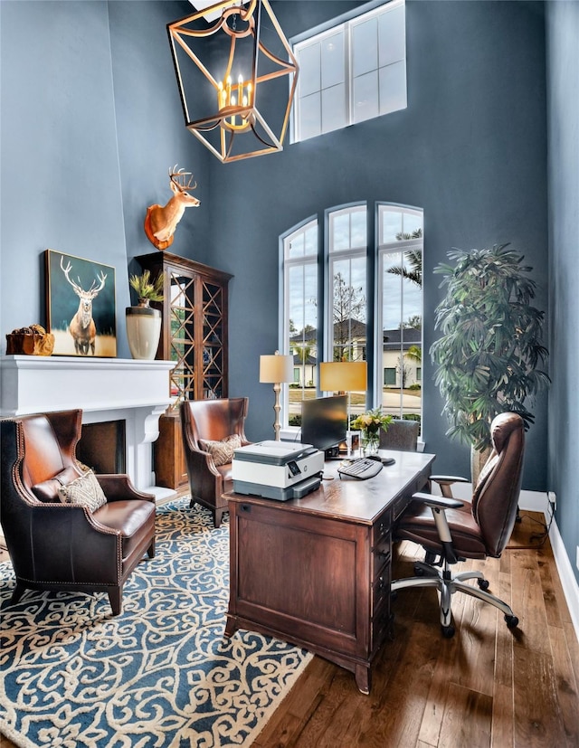 office area featuring dark hardwood / wood-style flooring, a chandelier, and a high ceiling