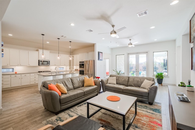 living room with ceiling fan, sink, light hardwood / wood-style flooring, and french doors